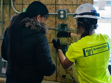 An electrician shows a student how to install an outlet