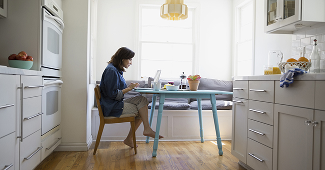 woman sitting at kitchen table on laptop