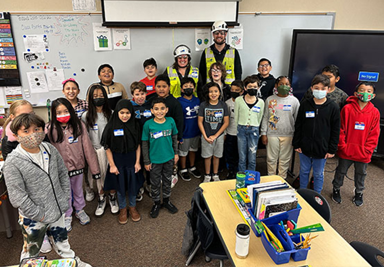 group of school kids with construction workers in classroom