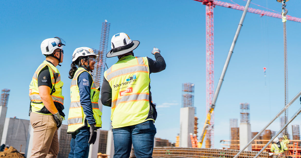 diverse construction workers pointing at crane