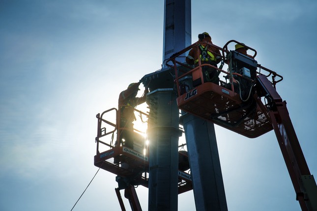 Team members working on pole in cranes