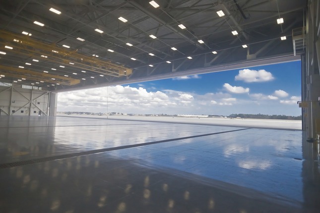 open hangar door to blue sky and white clouds