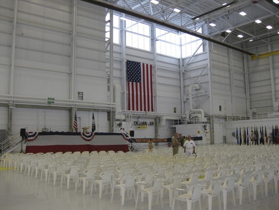 ceremony set up in hangar with white chairs and large American flag