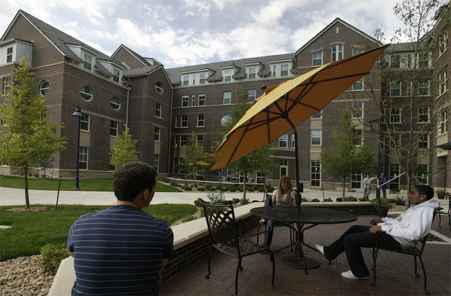 exterior of large brick building with yellow umbrella on patio