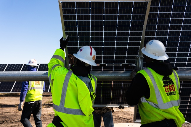construction workers behind solar panels