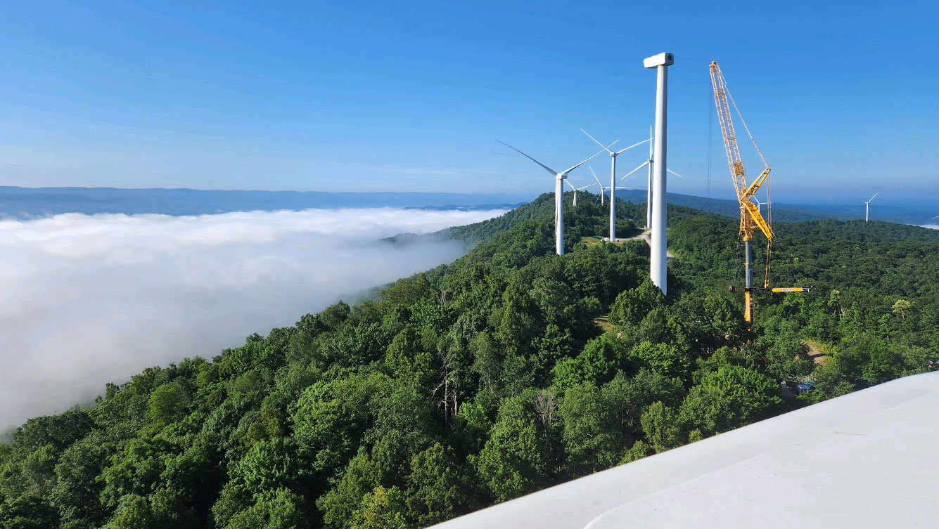 wind turbines in forest with clouds and sky