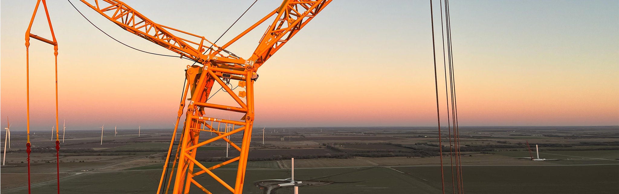 Large Yellow Crane Overlooking Wind Turbine Field at Sunset