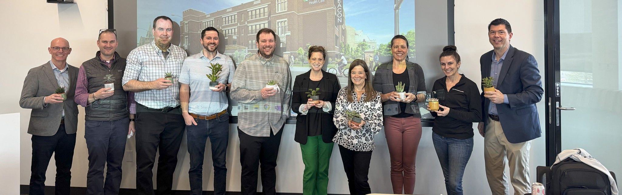 Group of professionals holding small plants
