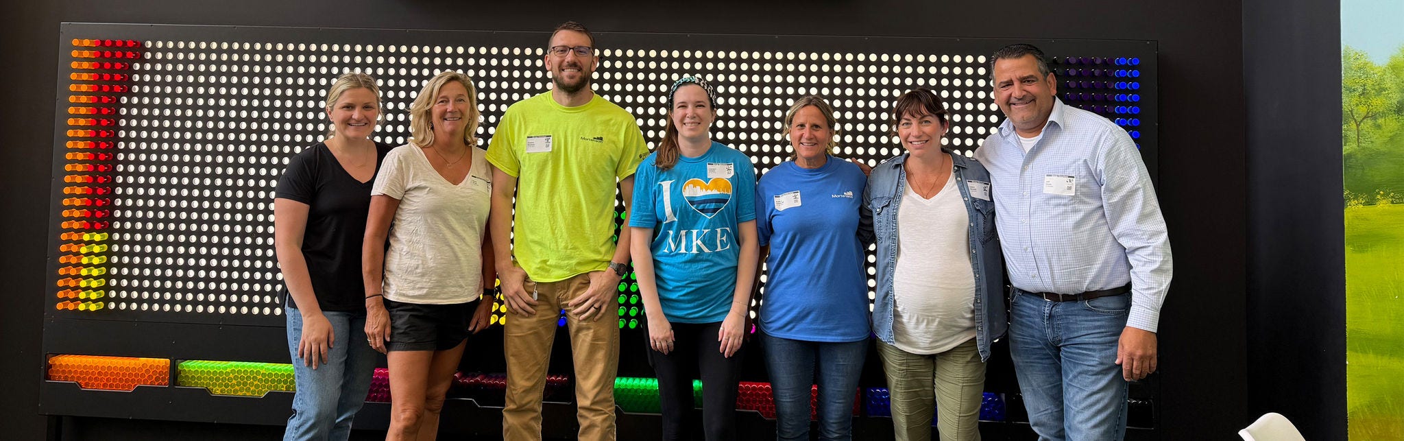 Group of adults posing in front of colorful wall display