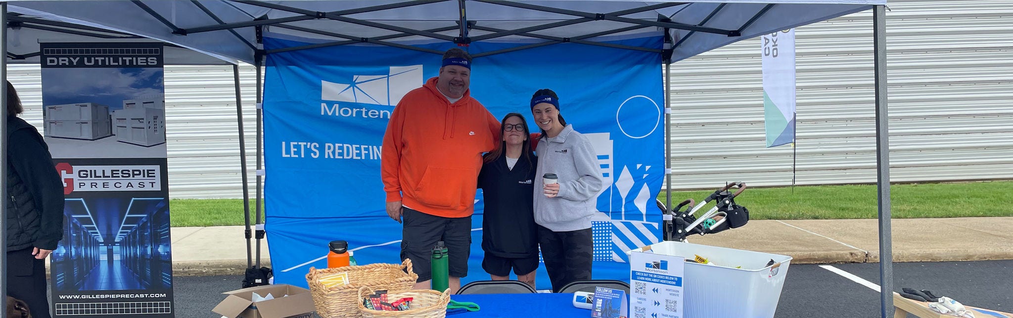 Outdoor event booth with three smiling participants