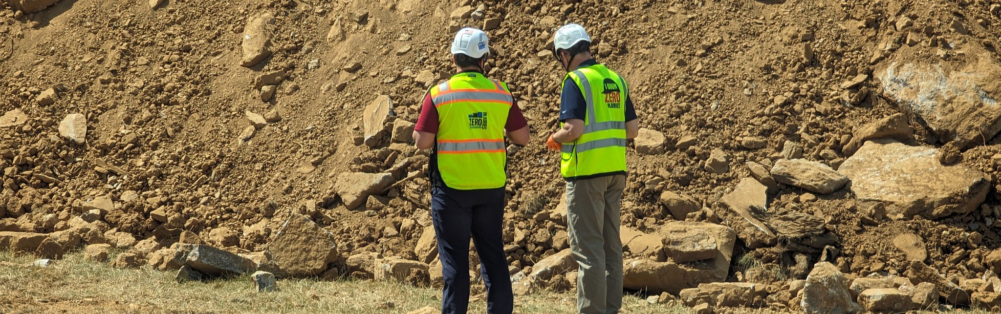 Construction workers inspecting rocky terrain